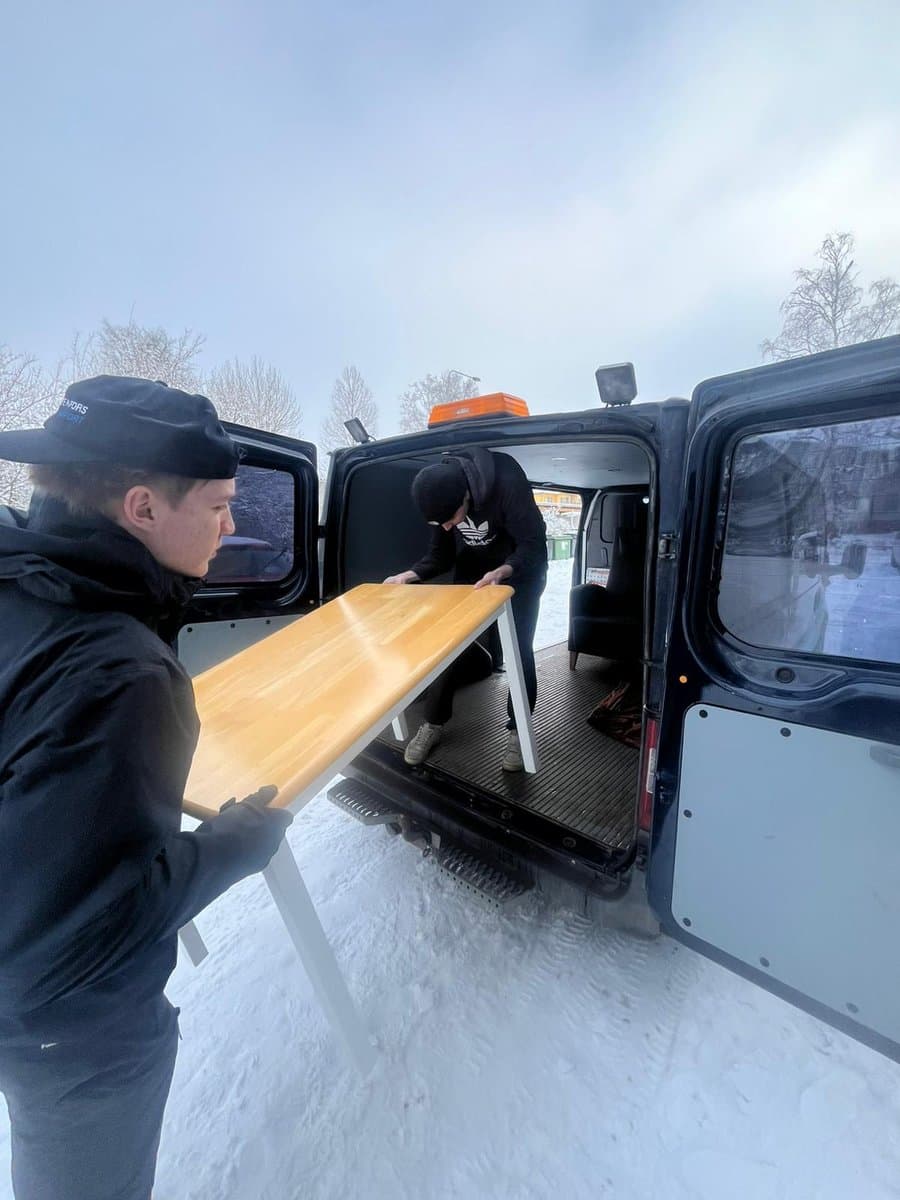 Kaksi kantajaa lastaa pöytää muuttoautoon talvella